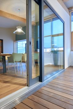 the inside of a house with wooden floors and sliding glass doors leading to an outdoor dining area