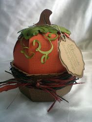 an orange pumpkin sitting on top of a white cloth covered box with a tag hanging from it's side