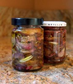 two jars filled with pickles sitting on top of a counter