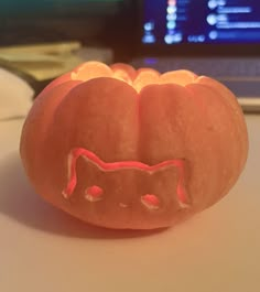 a carved pumpkin with a cat's face on it sitting in front of a computer