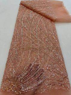 a piece of pink sequin fabric on a white tablecloth with gold glitters