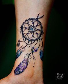 a woman's foot with a tattoo on it that has a small dream catcher