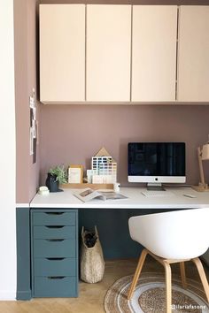 a desk with a computer on top of it in front of a wall mounted clock