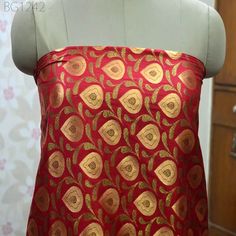 a mannequin wearing a red dress with gold designs on it's chest