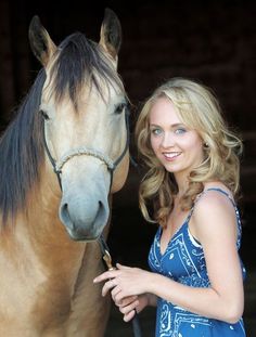 a woman standing next to a brown horse