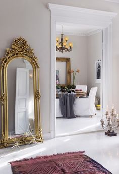 a room with a mirror, rug and chandelier