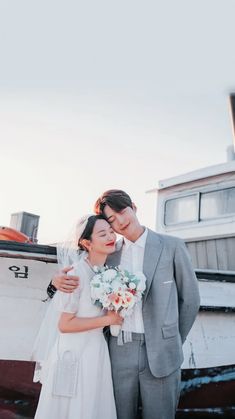 a bride and groom standing in front of a boat