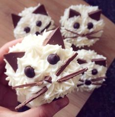 a person is holding some cupcakes with white frosting and chocolate on top