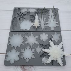 two trays with snowflakes, pine trees and pine cones cut outs on them