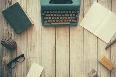 an old - fashioned typewriter sits on a wooden table surrounded by books, notebooks and other items