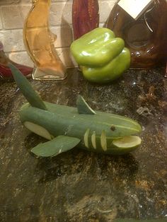 some green peppers are sitting on a counter top next to other bottles and vases