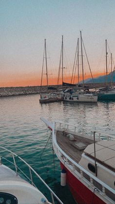 several boats are docked in the water at sunset