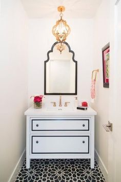 a bathroom with a white vanity and black and white tile flooring on the walls