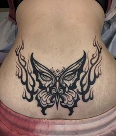 a woman's lower back with an owl tattoo on her stomach and wings around her neck