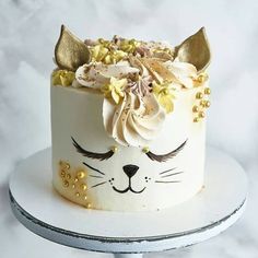 a white cake with gold decorations and a cat's face