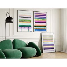 two paintings hang on the wall next to a green chair and lamp in a white room