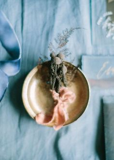 a gold plate with a flower in it on a blue table cloth next to some books