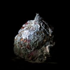 a rock covered in lots of different types of rocks and gravel on a black background