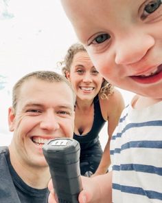 a man holding a remote control next to a woman and smiling at the camera boy