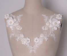 the back of a mannequin with white flowers on it's neckline