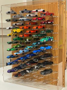 a wooden display case filled with lots of toy cars on top of a white table