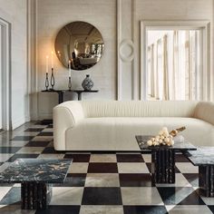 an elegant living room with black and white checkered flooring, large round mirror on the wall