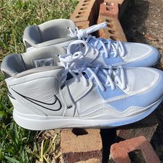 a pair of white sneakers sitting on top of bricks