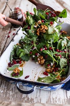 a salad with spinach, walnuts and feta cheese in a blue dish