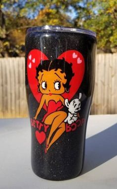 a black cup with an image of betty bobs on it and a red heart