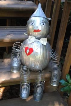 a metal scarecrow sitting on top of some tin canisters in the shape of a pumpkin