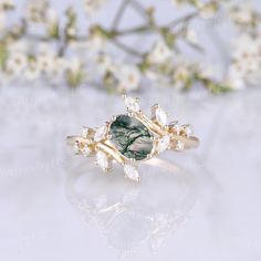 a ring with a green stone surrounded by white flowers