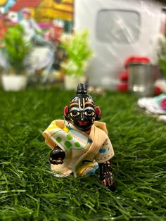 a small figurine sitting on top of green grass