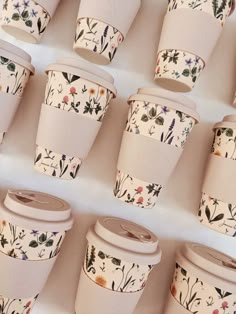 coffee cups with floral designs are lined up on a table in front of each other