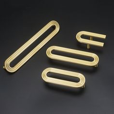 three gold metal handles and two clips on a black surface, with the top one open