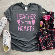 a t - shirt that says teacher of tiny hearts next to some shoes and flowers