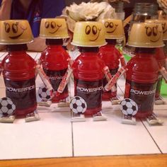 four bottles with faces drawn on them sitting on a table next to each other and one has a soccer ball painted on it