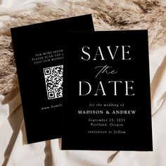 two black save the dates cards on top of a white bed sheet with fur in the background