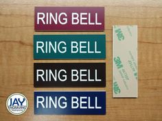 four different colored street signs on a wooden surface with the words ring bell, ring bell and ring bell