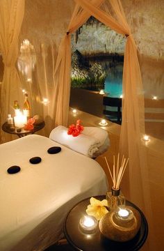 a spa room with candles and towels on the bed