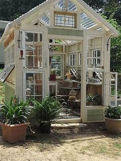 a small white house sitting in the middle of a yard next to some potted plants