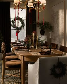 a dining room table with candles and wreaths hanging from it's centerpiece