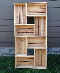 a wooden shelf sitting in the grass next to a building