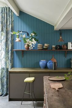 a kitchen with blue walls and wooden shelves