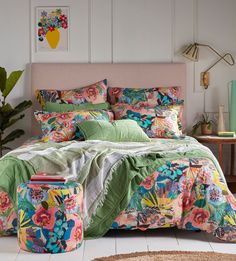 a bed with colorful comforters and pillows in a room next to a rug on the floor