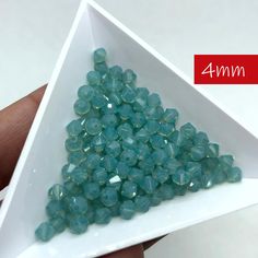 there is a small pyramid shaped object made out of green glass beads in the shape of a triangle