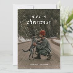 a christmas card with a photo of a man and his dog sitting on the road