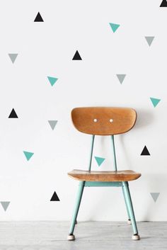 a wooden chair sitting in front of a wall with triangles on it's side