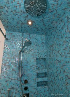 a shower with blue tiles in the shower head and hand held shower faucet