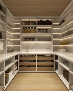 an organized pantry with lots of shelves and drawers on the wall, along with wooden flooring