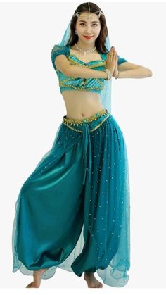 a woman in a blue belly dance outfit with her arms out to the side and one hand on her hip